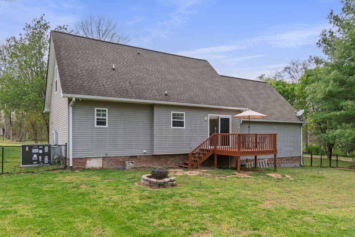 The rear exterior highlights easy deck access through the sliding door and a large, open lawn.