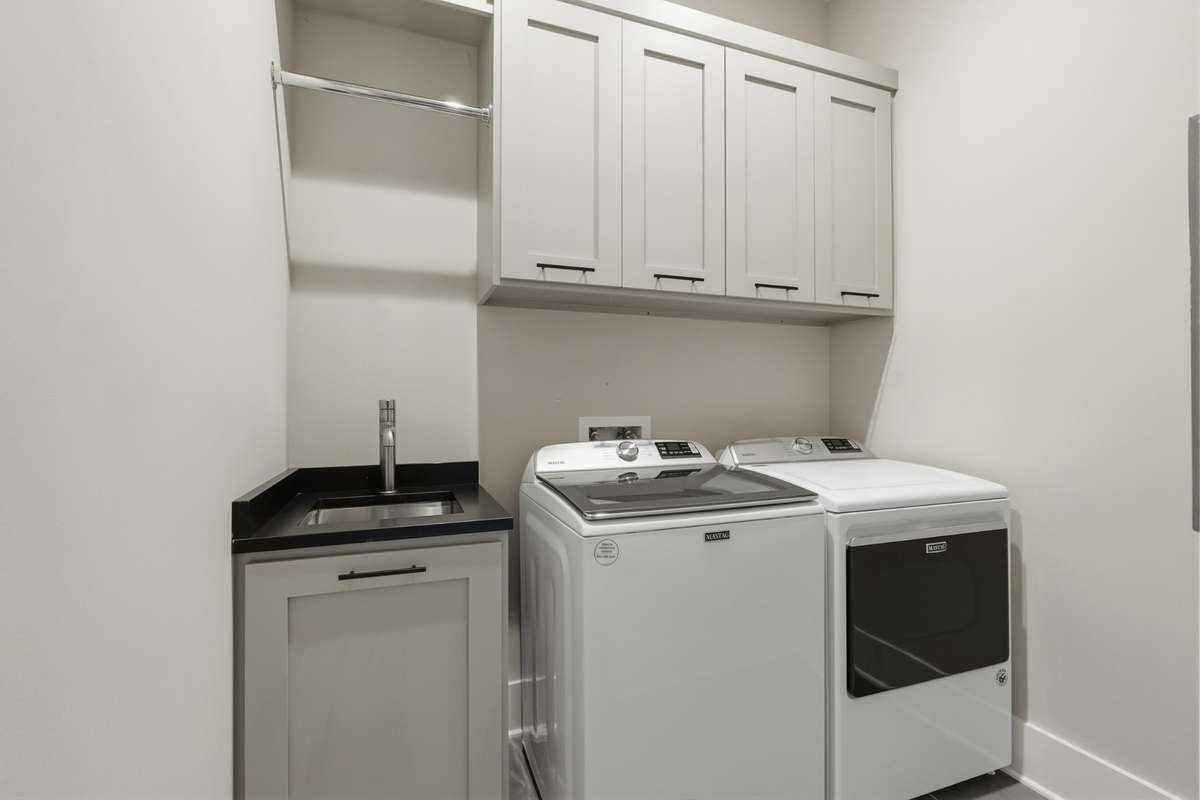 Spacious laundry room with built-in cabinetry, utility sink, and additional storage.