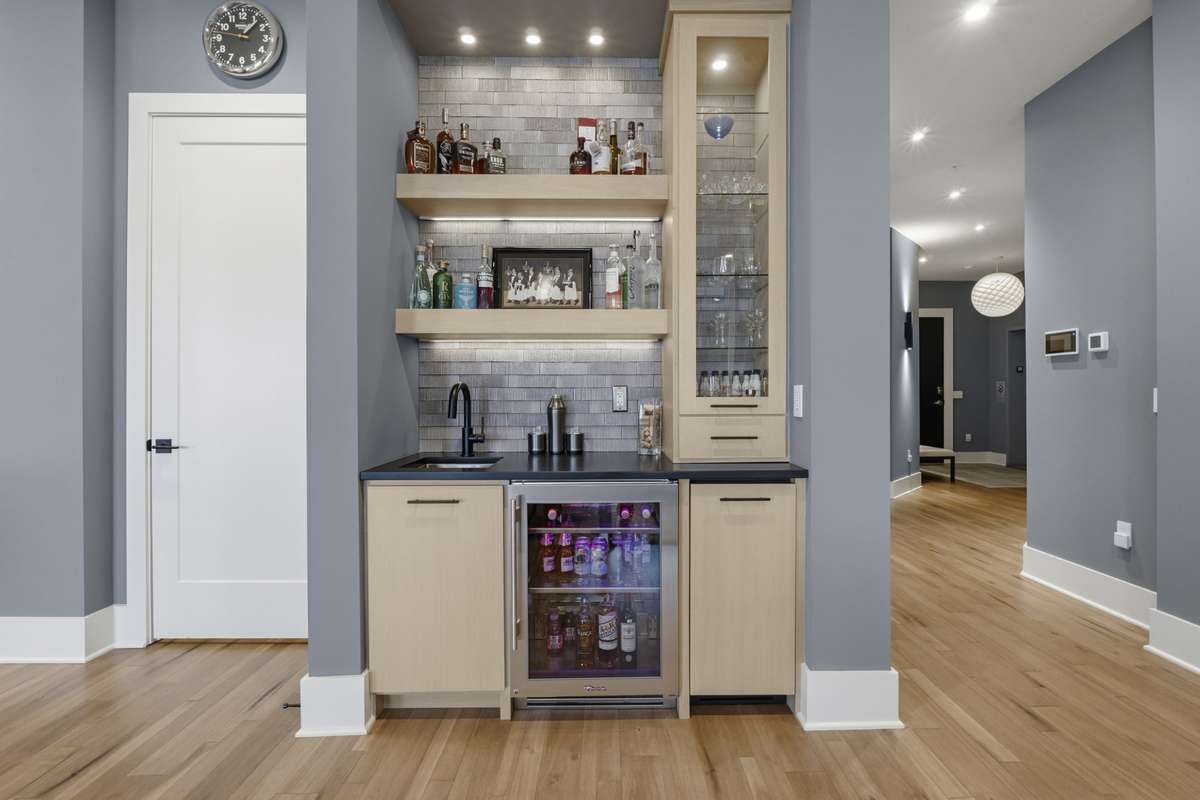 Custom wet bar with beverage fridge, built in ice machine, upper display shelving, and designer tile backsplash- perfect for entertaining.