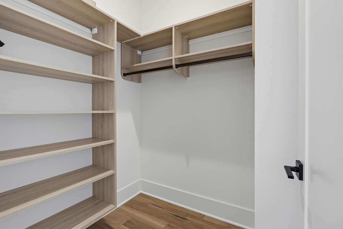 Large Walk-In Closet with CUSTOM BUILT-IN SHELVING and ample storage.