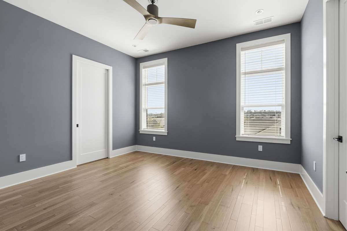 Spacious secondary bedroom with large windows, abundant natural light, and hardwood flooring throughout.