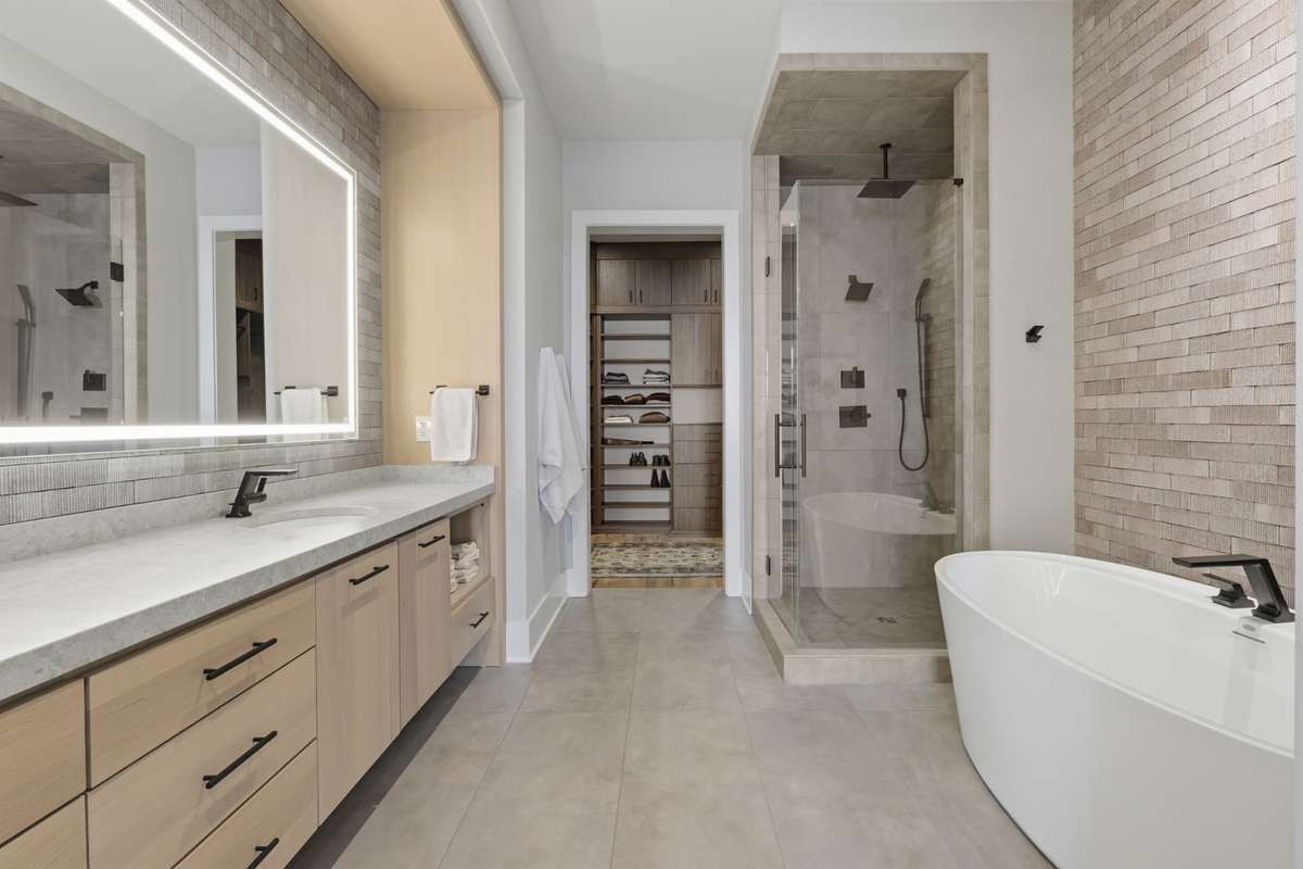 Spa-inspired primary bath featuring HEATED FLOORS, FLOATING VANITIES, DESIGNER LIGHTED MIRRORS & CUSTOME TILE.