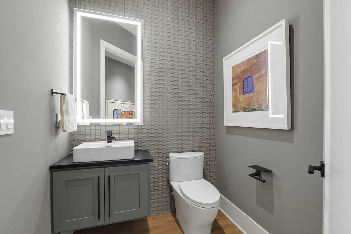 Stylish half bath located off the foyer featuring floating vanity, designer lighted mirror, and custom accent wall.