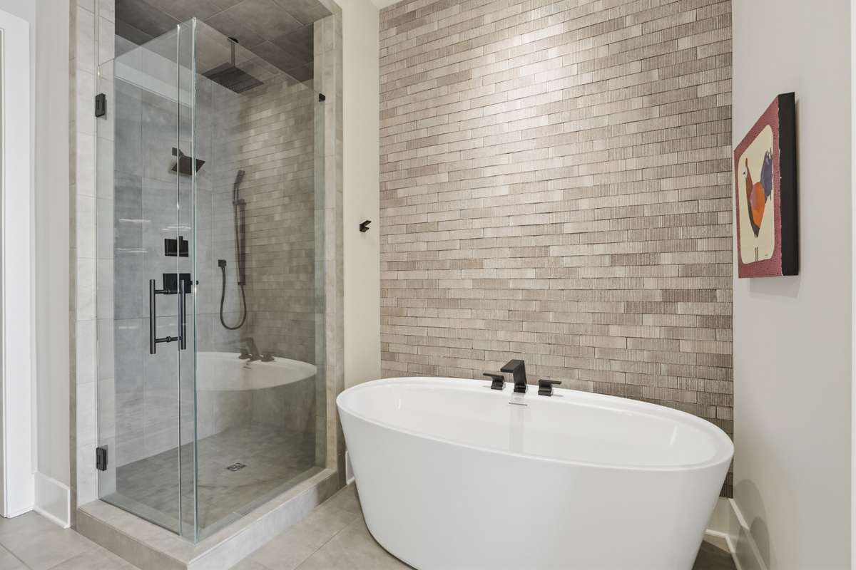Unwind in a freestanding soaking tub alongside a luxury walk-in shower surrounded by custom tile and elevated finishes.