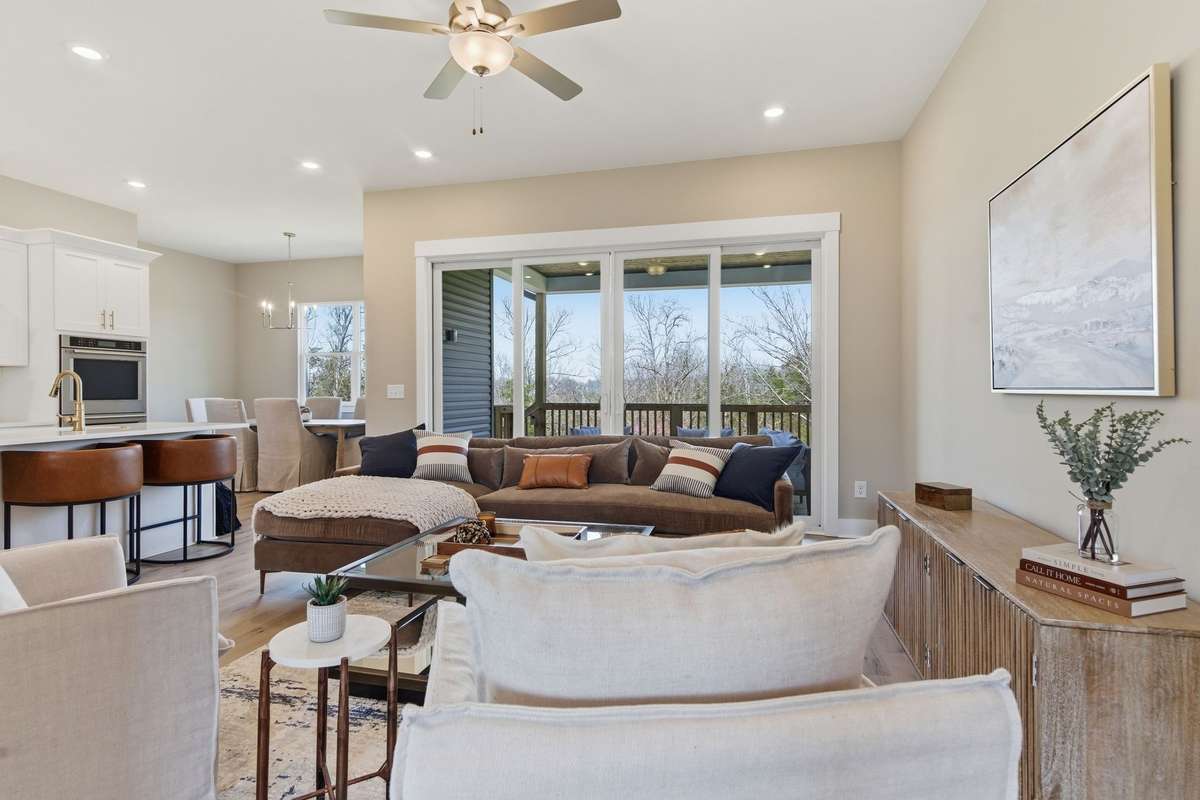 The Great Room has double sliding doors that showcase the covered deck and trees behind the home!