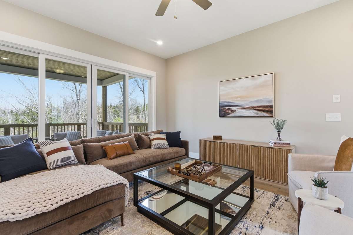 The Great Room has double sliding doors that showcase the covered deck and trees behind the home!