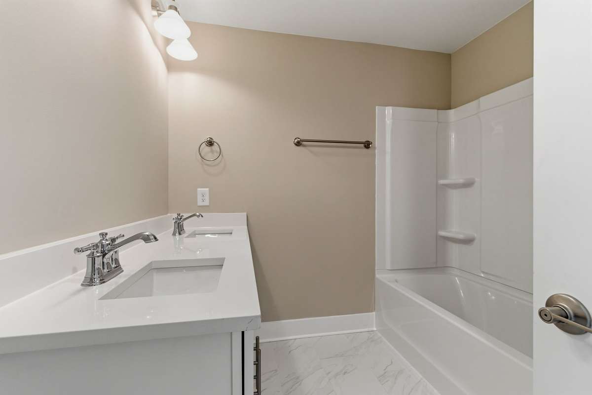 The second floor guest bath features a double vanity with quartz counters
