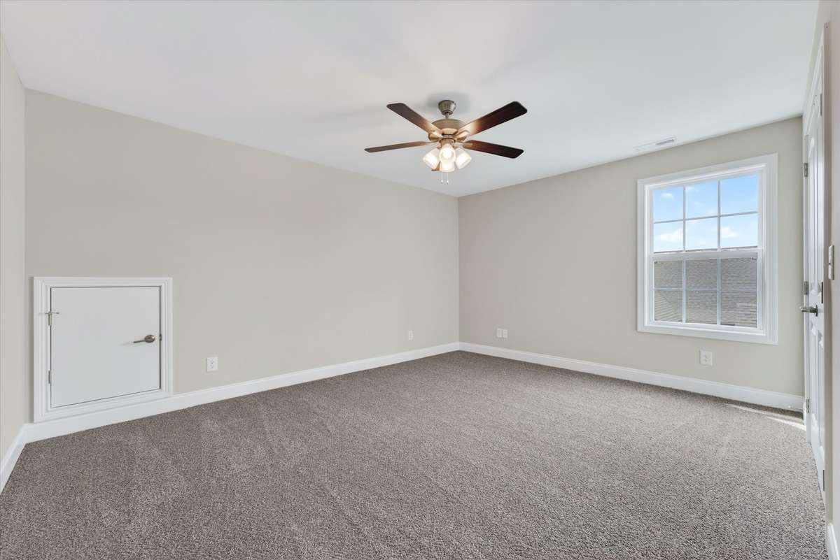 Spacious bedroom with ceiling fan and natural light.