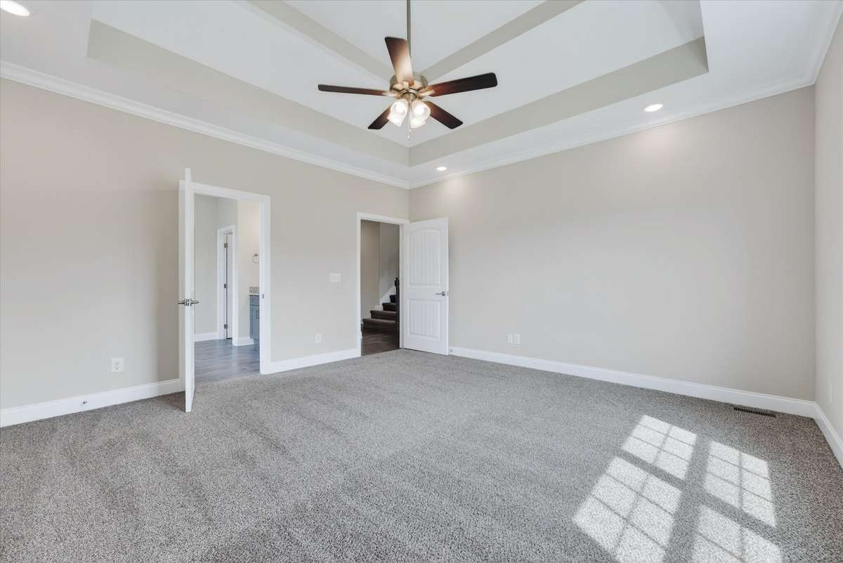 Generously sized primary bedroom with plush carpet and neutral tones