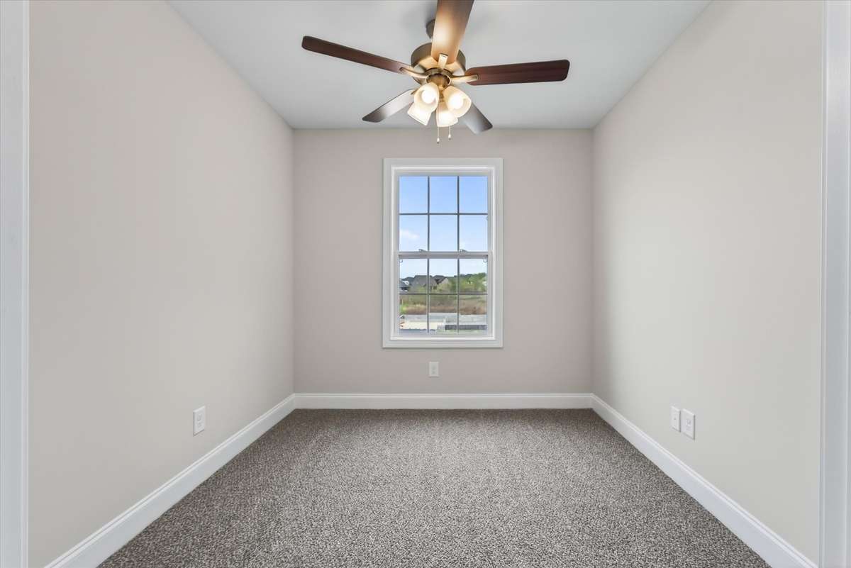 Bright secondary bedroom with ceiling fan and window views