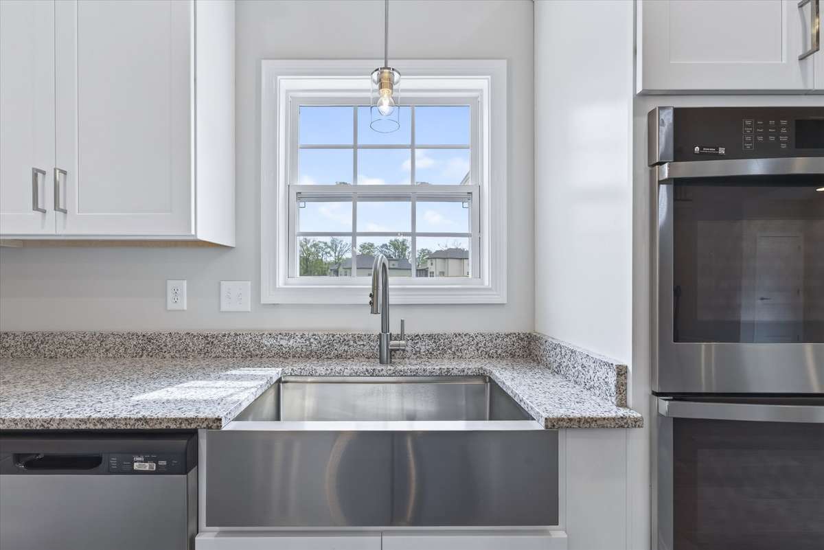 Kitchen featuring granite countertops, stainless sink, and bright window.
