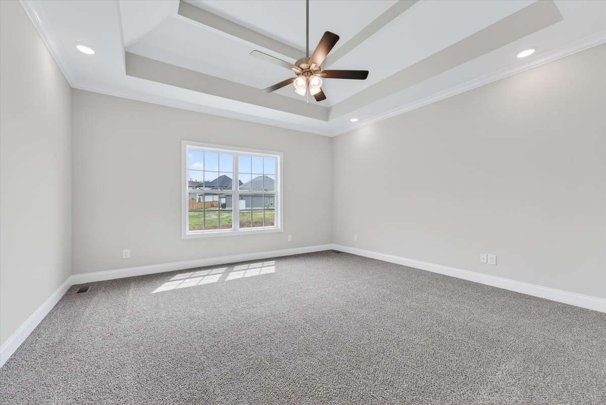 Spacious primary suite with tray ceiling and natural light