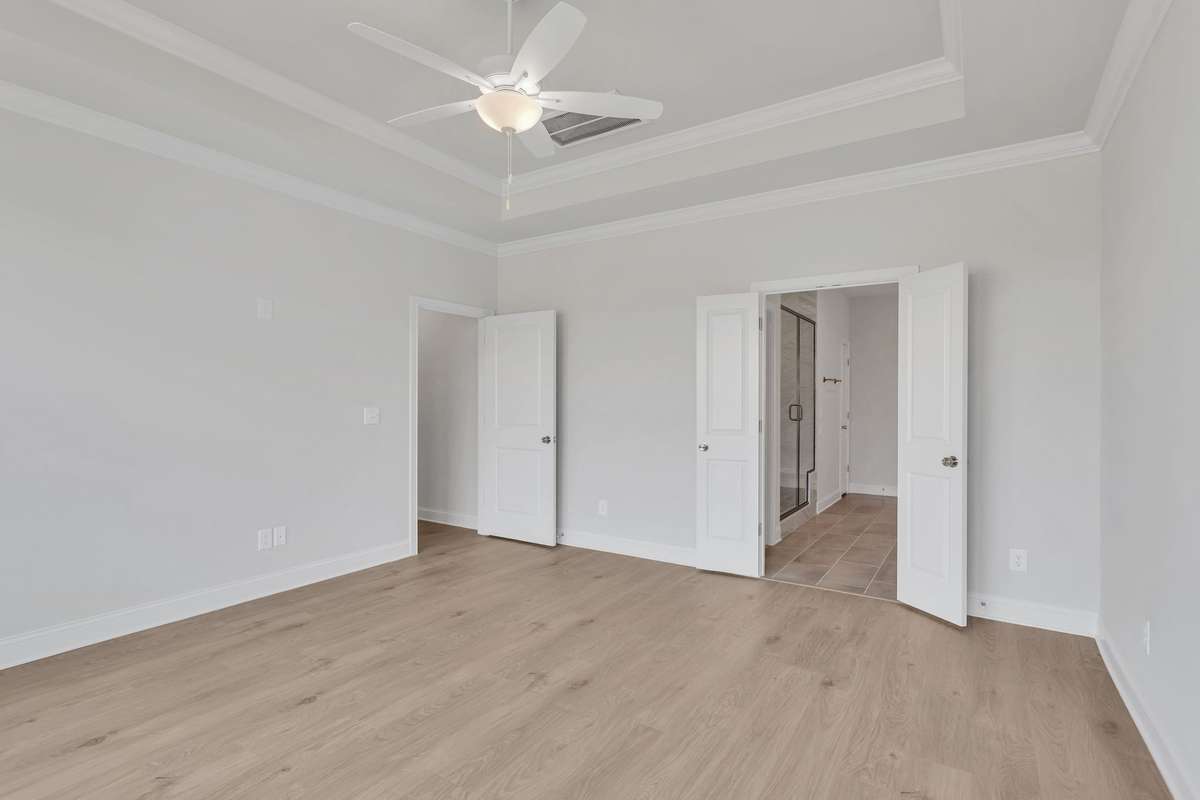 Primary bedroom boasts trey ceiling and fan