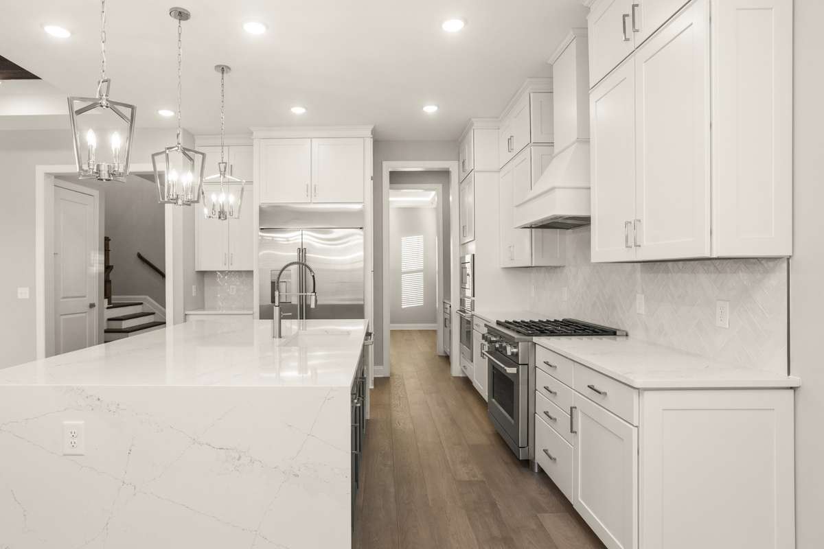 View of kitchen peeking into dining room on the right and the hall and stairs to the left