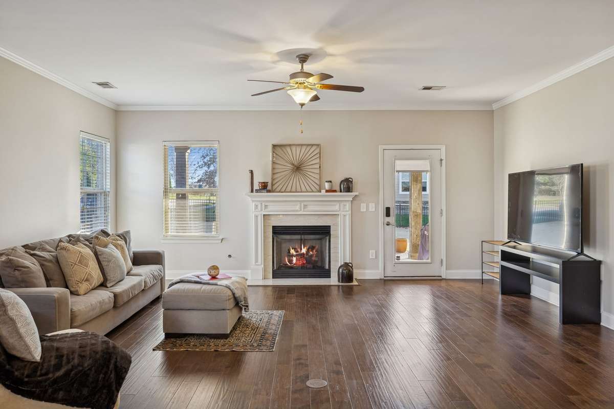 Spacious living area with hardwood floors and abundant natural light—perfect for gathering.
The fireplace is natural gas. The door leads to the covered back porch and fenced in backyard