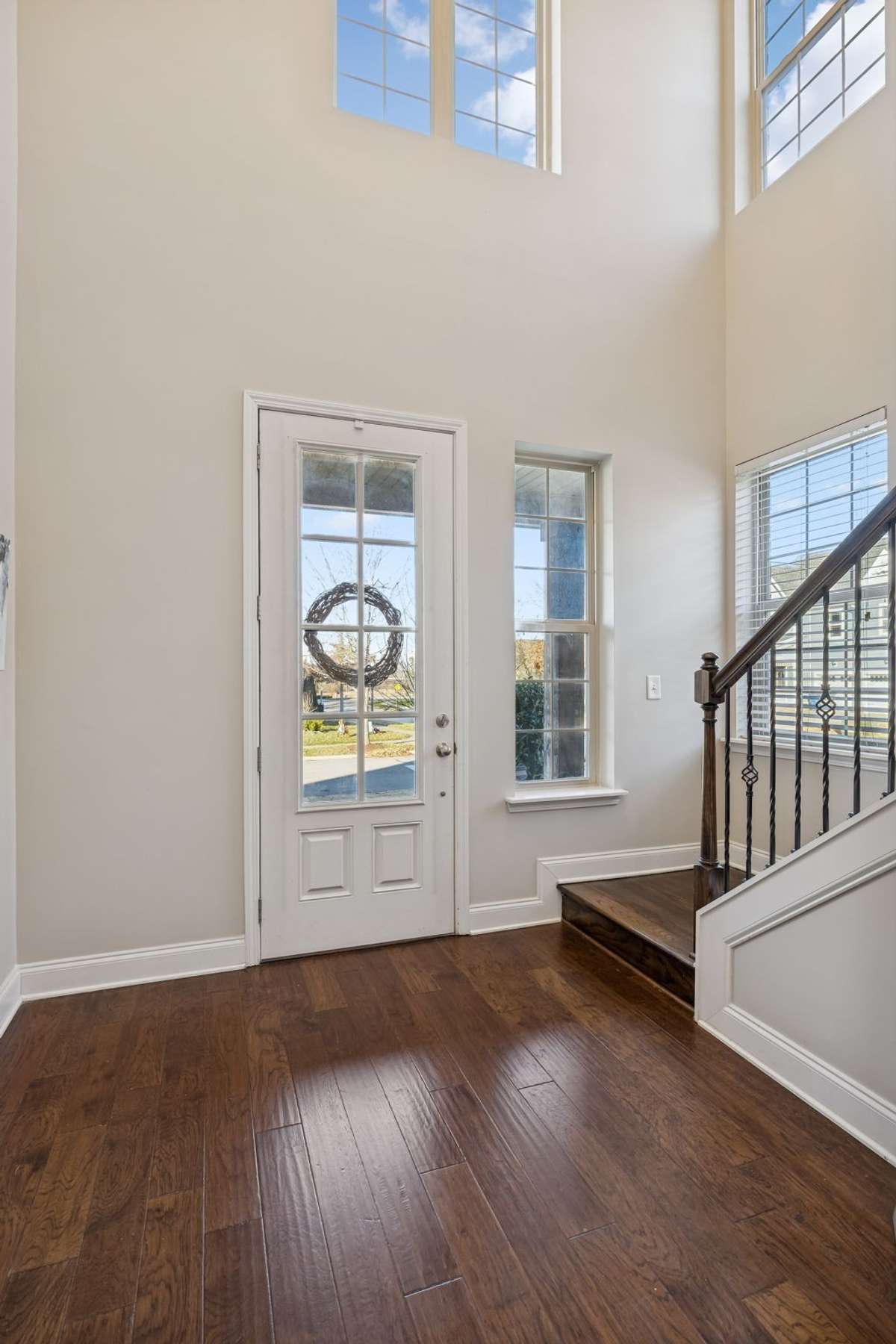 Bright two-story foyer filled with natural light and elegant hardwood flooring.
