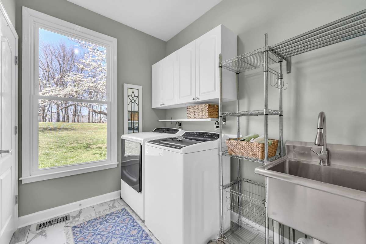 This spacious laundry room with stainless steel wash wink + tile flooring + extra storage space