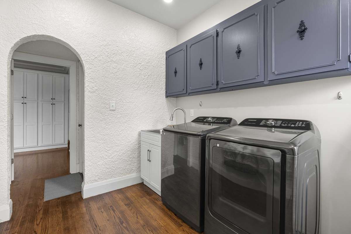 Spacious laundry room located off the kitchen with utility sink. Cabinets were repurposed from the original kitchen cabinets.
