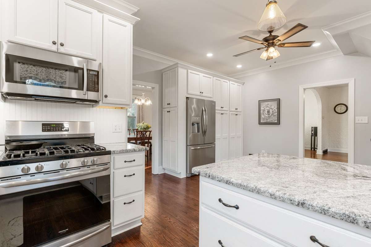Kitchen is equipped with stainless appliances and a white farmhouse sink.