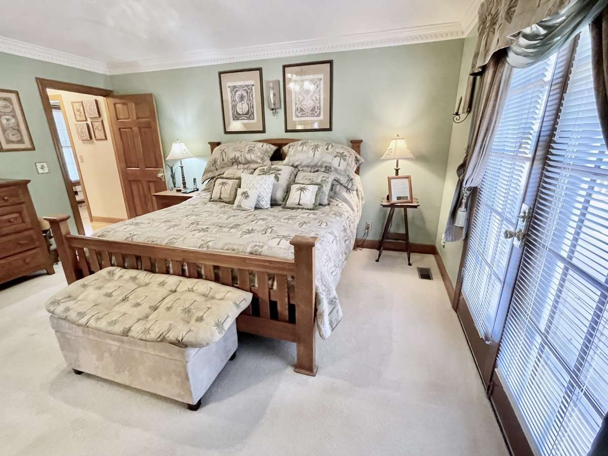 The spacious primary bedroom accommodates a king-size bed and opens to the back deck, overlooking a large, private backyard—creating a serene retreat.