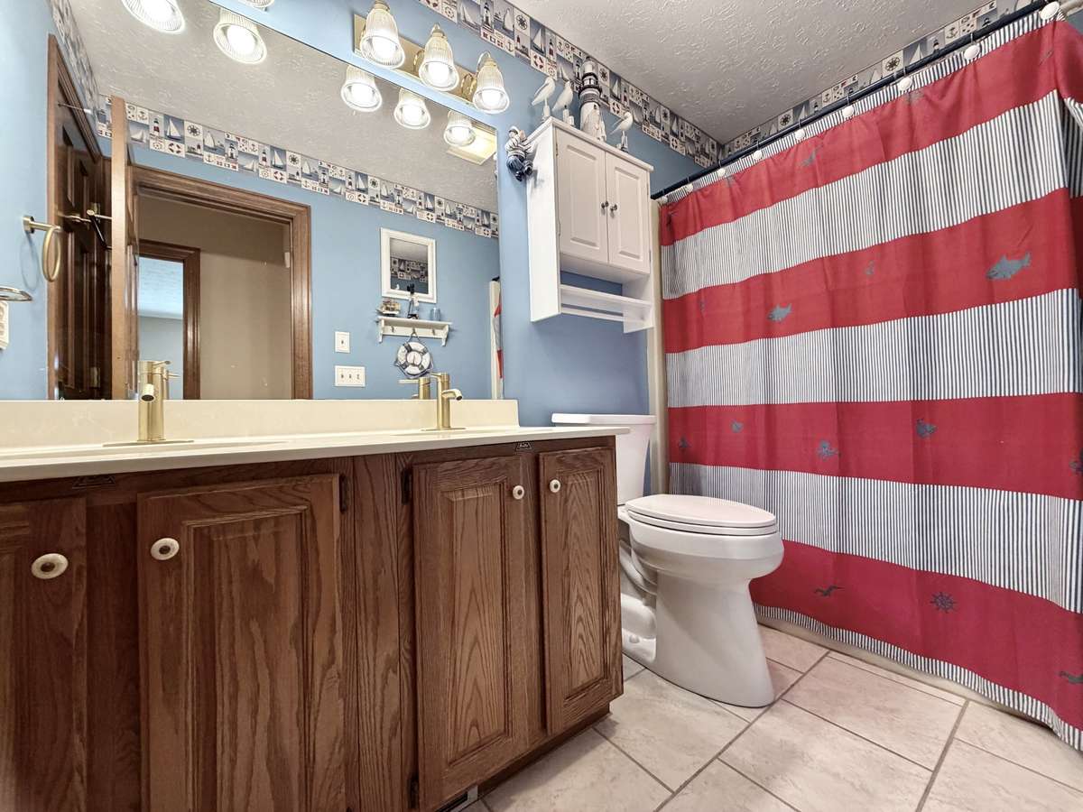 Raised vanity with double sinks & tile floor in guest bathroom.