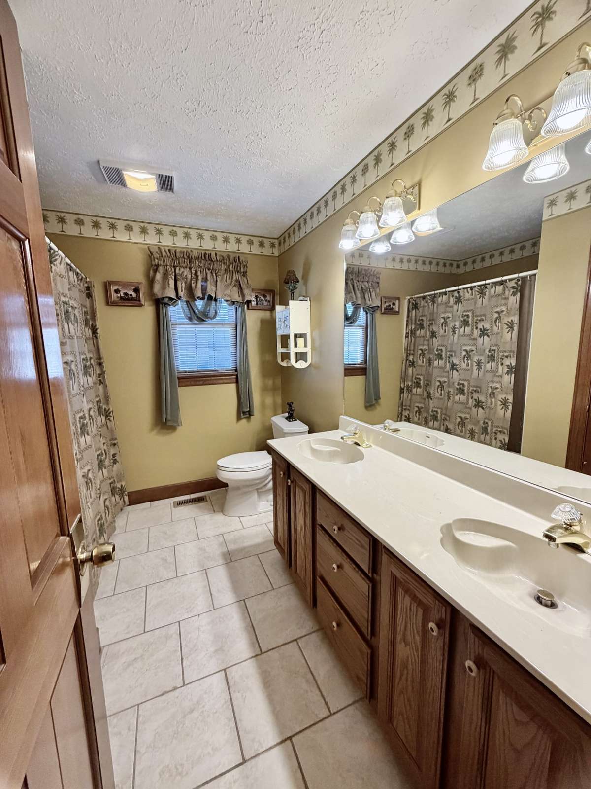 Primary bathroom with window, double sinks, ample cabinet & drawer space, tile floor & large linen closet.