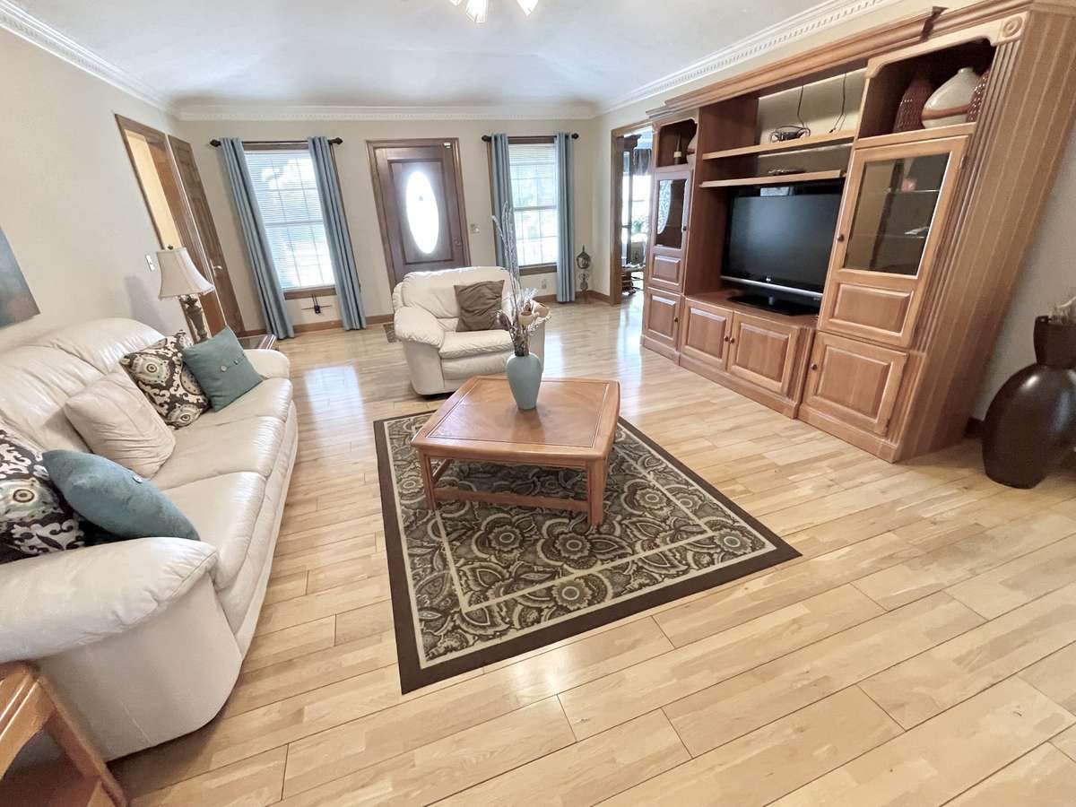Enjoy a spacious living room with wide-plank hardwood floors, an elegant raised tray ceiling, and a fireplace that adds architectural appeal.
