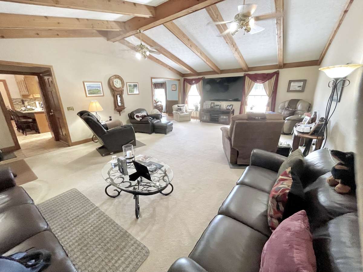 Huge family room with vaulted ceiling and exposed wood beams, creating a warm and inviting centerpiece for gatherings.