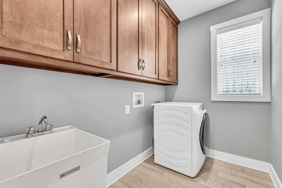 The laundry room has a utility sink and lots of cabinet storage. The dryer stays.