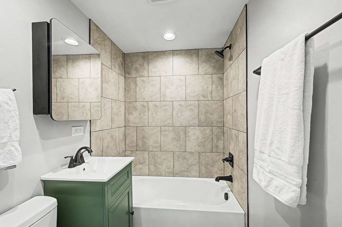This bath has a new tiled shower, new vanity, new towel bars and new mirror.