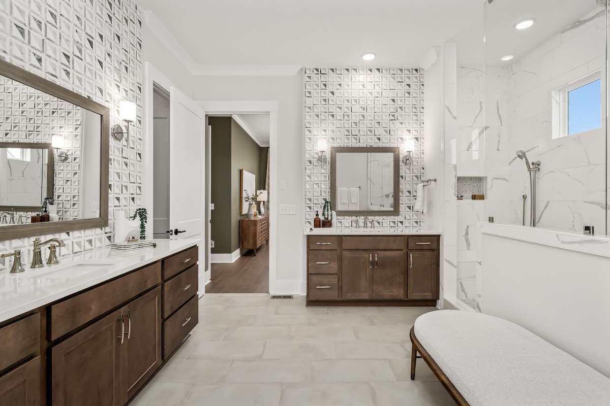 Primary bathroom with oversized shower.  Tiled walls over each vanity give way to the elevated look of this space.