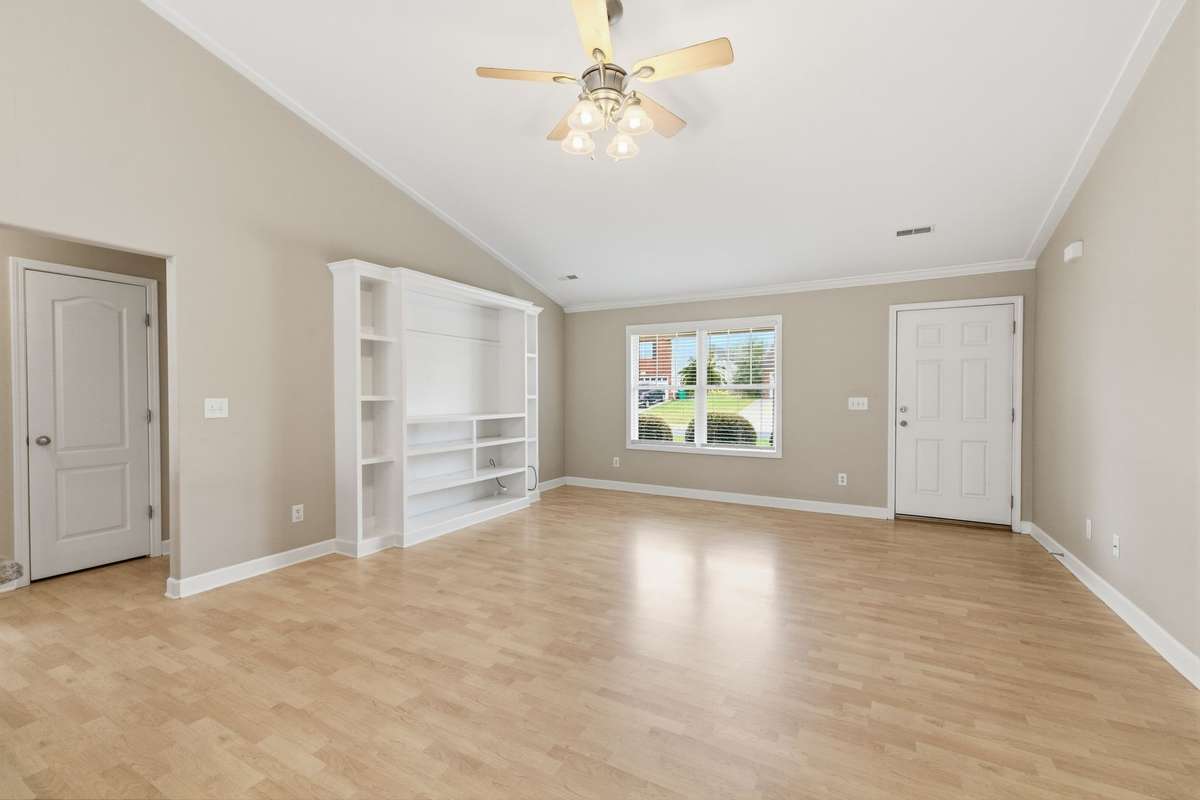 Living room and kitchen area is open with vaulted ceilings, built-in entertainment shelf, and an absence of Carpet!
