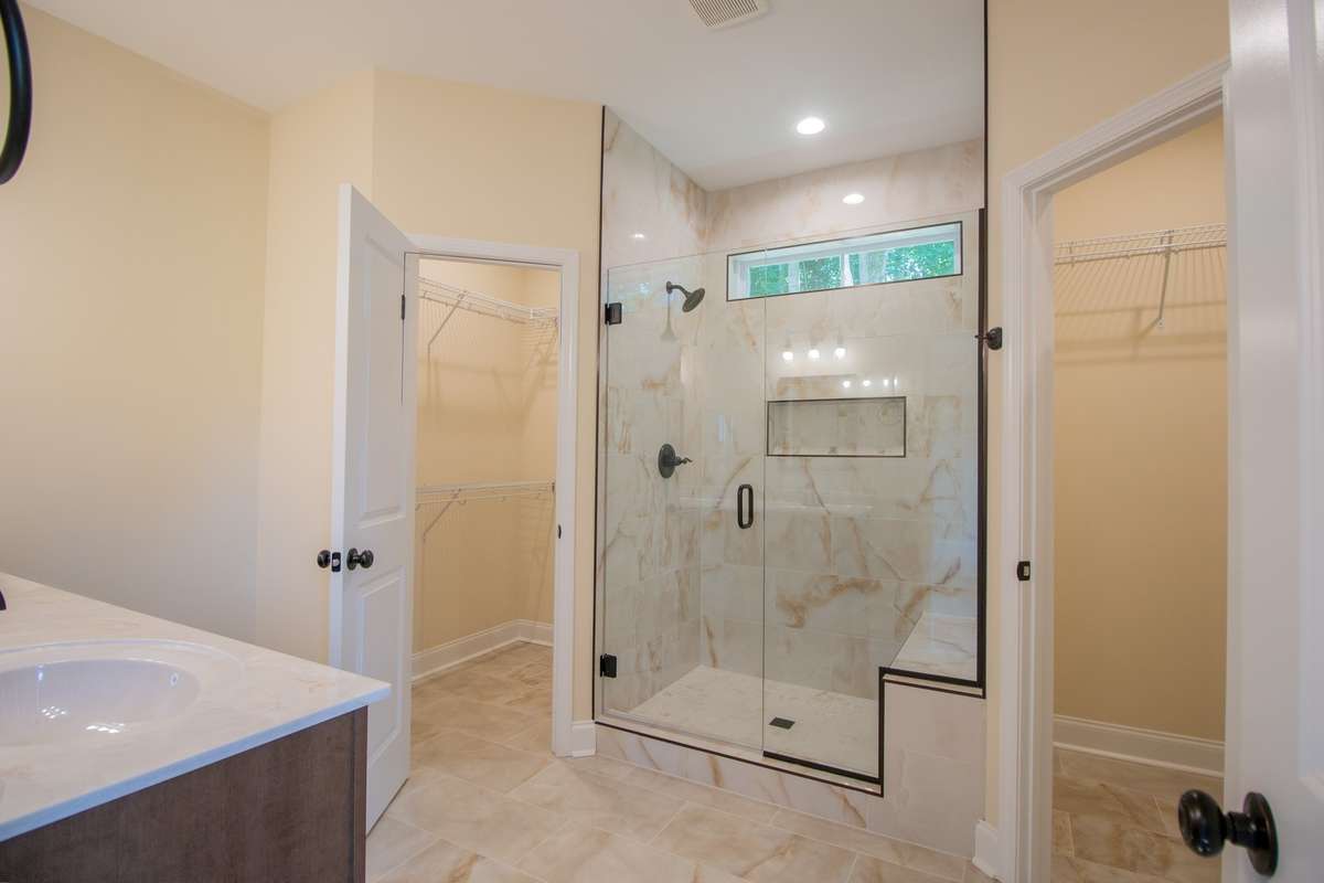 EXAMPLE>>>Primary Bathroom Features a Huge Tile Shower with a Bench and Window for Natural Lighting, Double Vanity and Two Walk-in Closets!