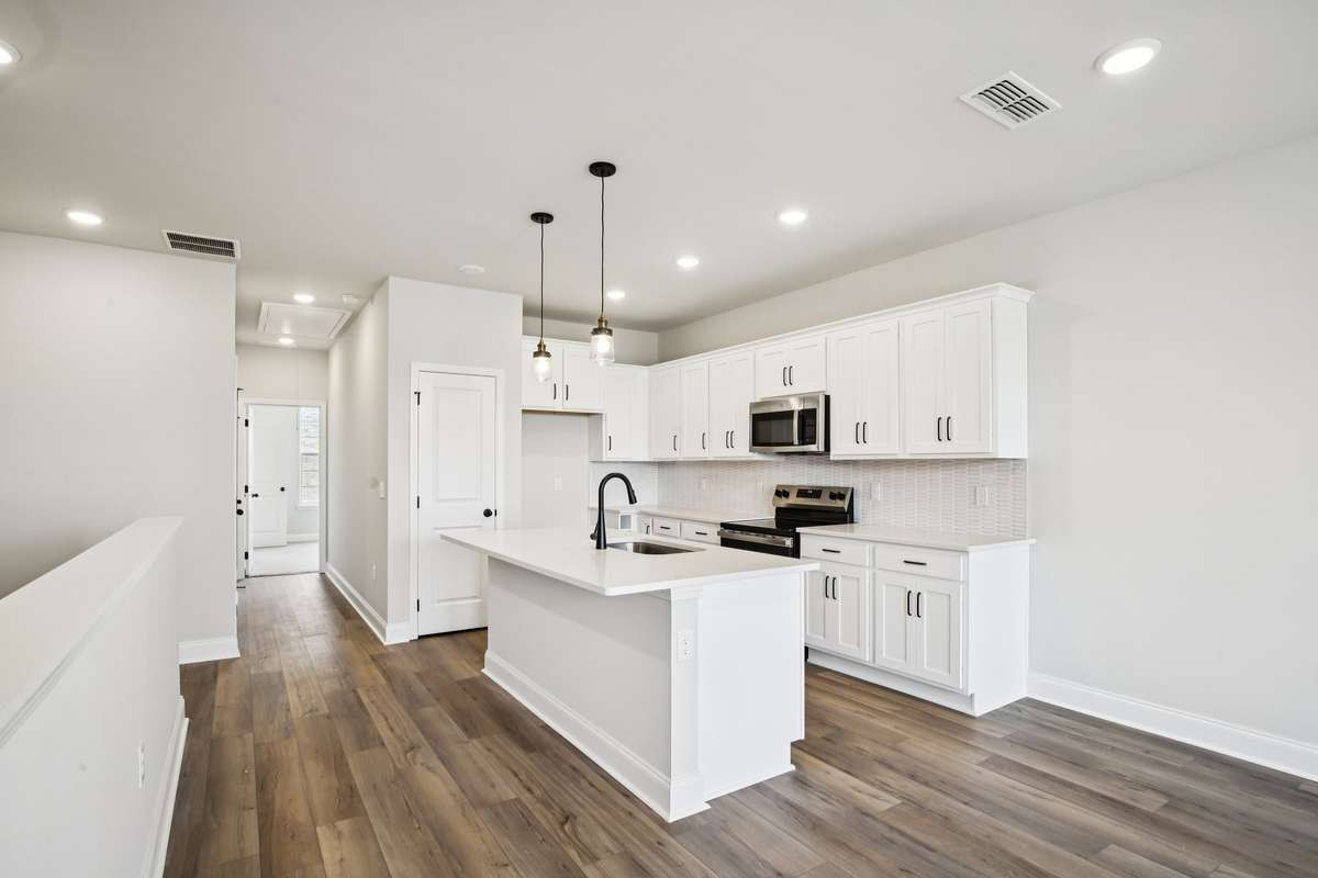 The kitchen showcases white cabinetry with soft-close doors, quartz countertops, and a stylish backsplash, creating a bright and modern space that’s both functional and beautiful.