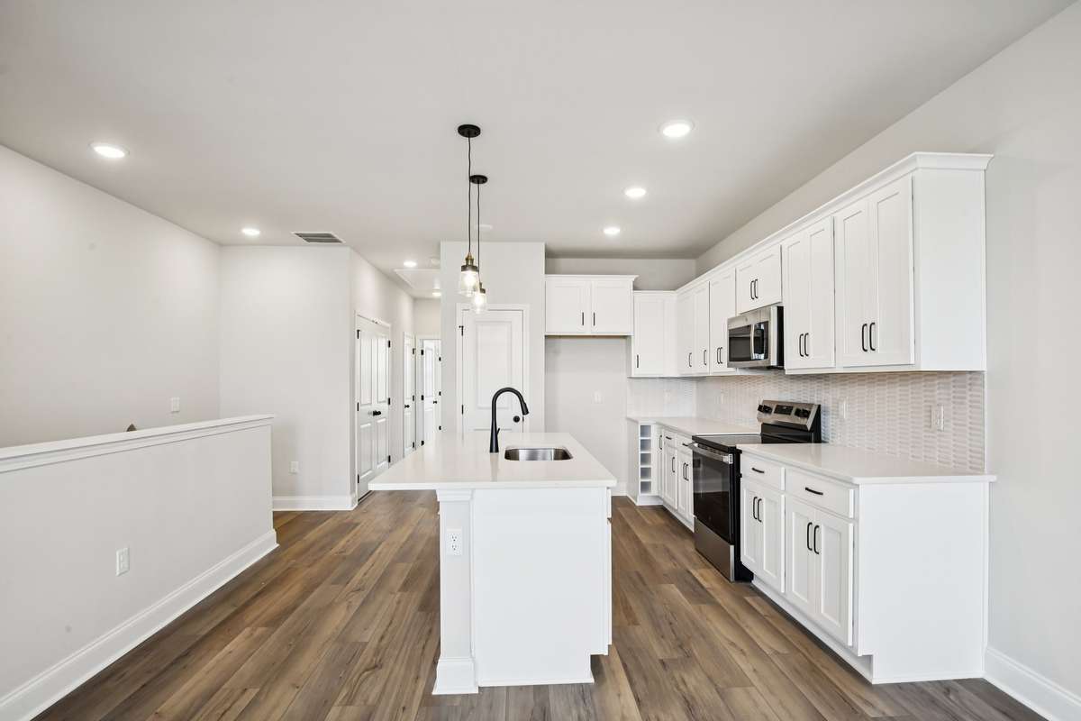 Stainless steel appliances and pendant lighting complete the kitchen, adding a sleek, modern touch to the space.