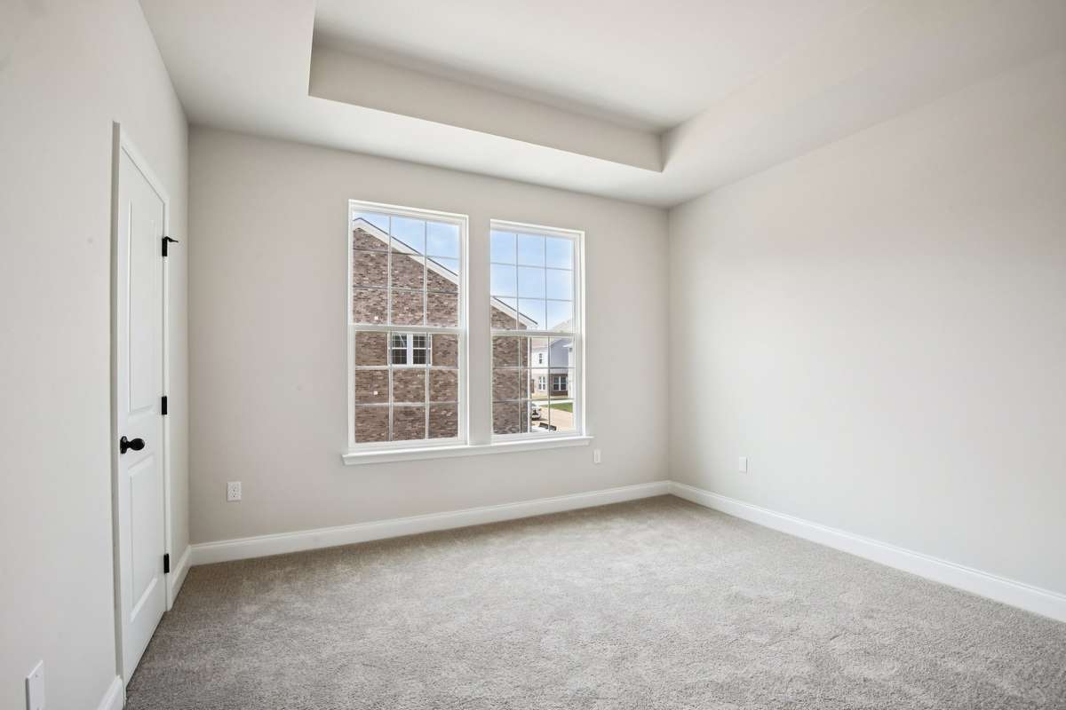 The primary bedroom features a tray ceiling that adds a sense of height and elegance, making the space feel open and inviting.