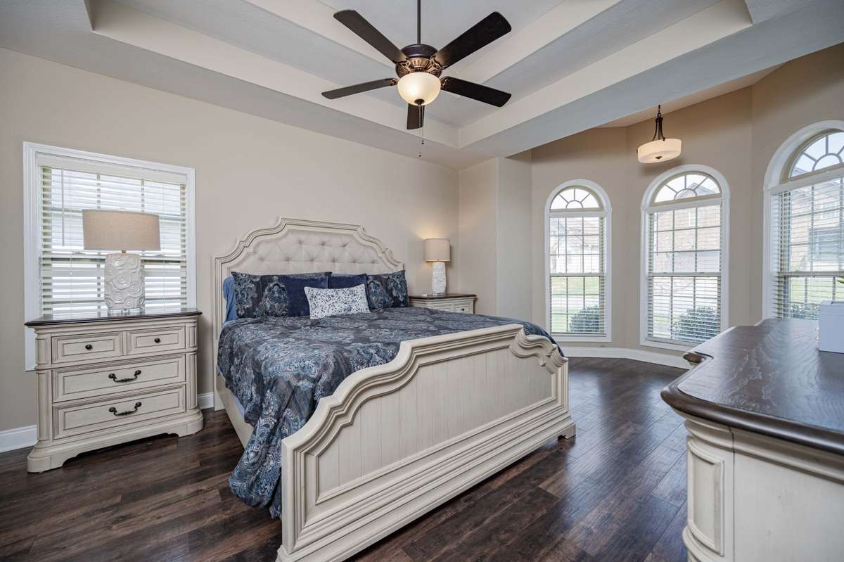 Primary bedroom with coffered ceiling and arched windows that frame the view.