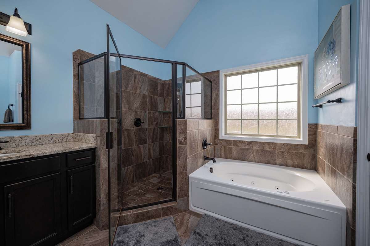 Separate tub and shower with the jetted tub positioned under the window to catch natural light during an evening soak.