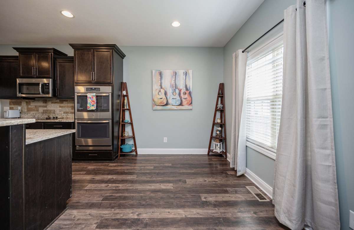 Kitchen opens to the breakfast area with built-in microwave and double-oven setup that keeps everything within reach while cooking.