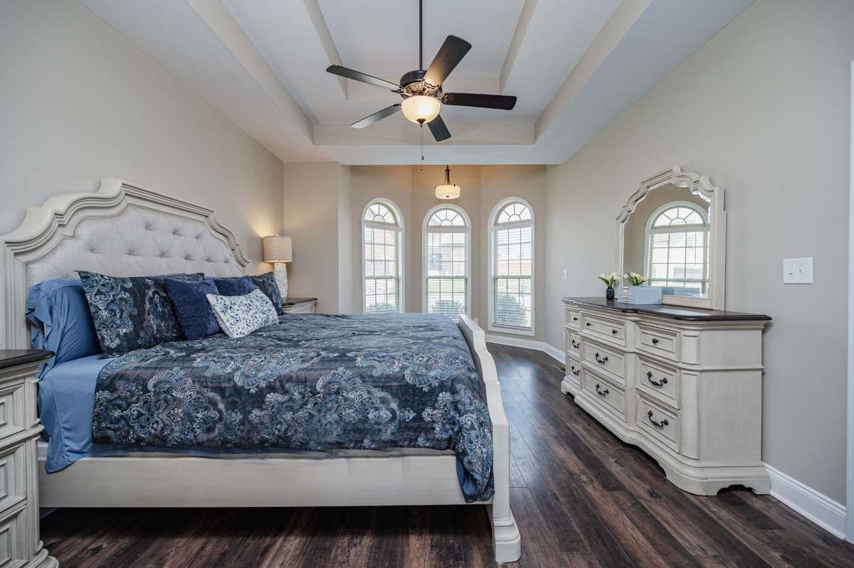 Tray ceiling with exposed beams and arched windows give this bedroom an elevated feel when you walk in.