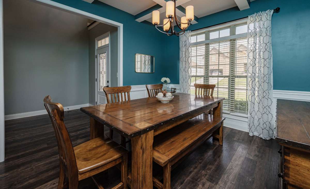 Formal dining room with coffered ceiling detail and rich teal walls creates a separate space for sit-down meals away from the everyday kitchen area.