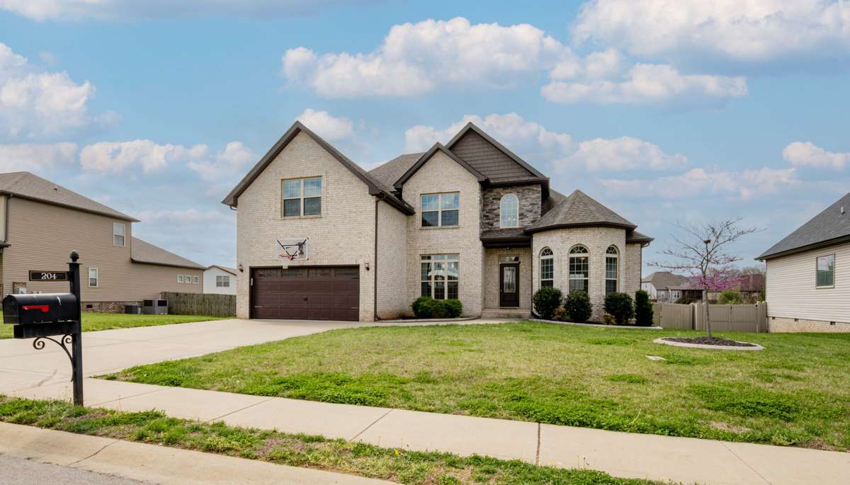 Welcome to 204 Bluebriar Trace, Clarksville, TN. Two-story contemporary in Farmington featuring light brick exterior with a large front yard and circular driveway approach.