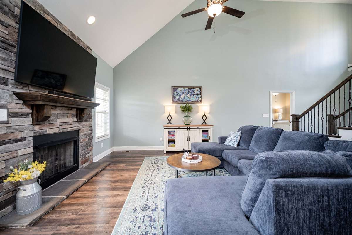 Stone fireplace with a dark wood mantel anchors this end of the room while built-in storage keeps things organized underneath the stairs.