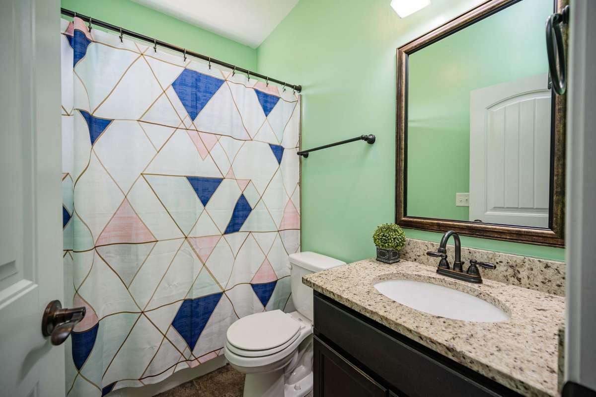 Full bathroom with granite countertop keeps daily routines organized with good counter space around the sink.