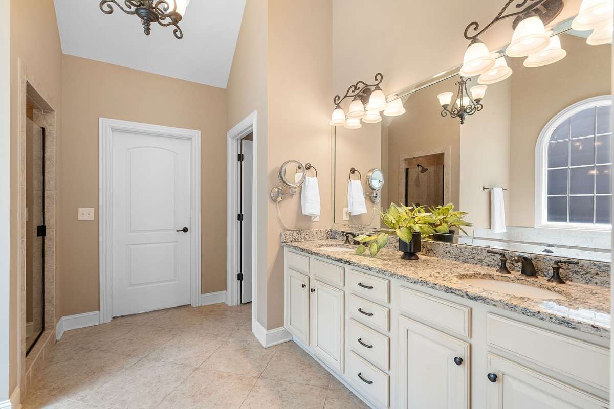 Primary bathroom with double vanities and granite countertops.