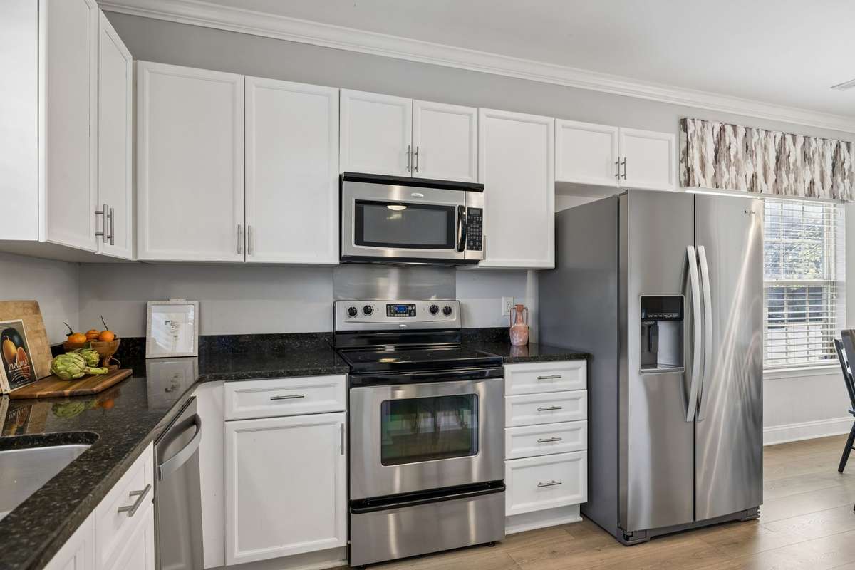 White cabinetry, stainless appliances and stylish granite countertops give the kitchen a modern feel.