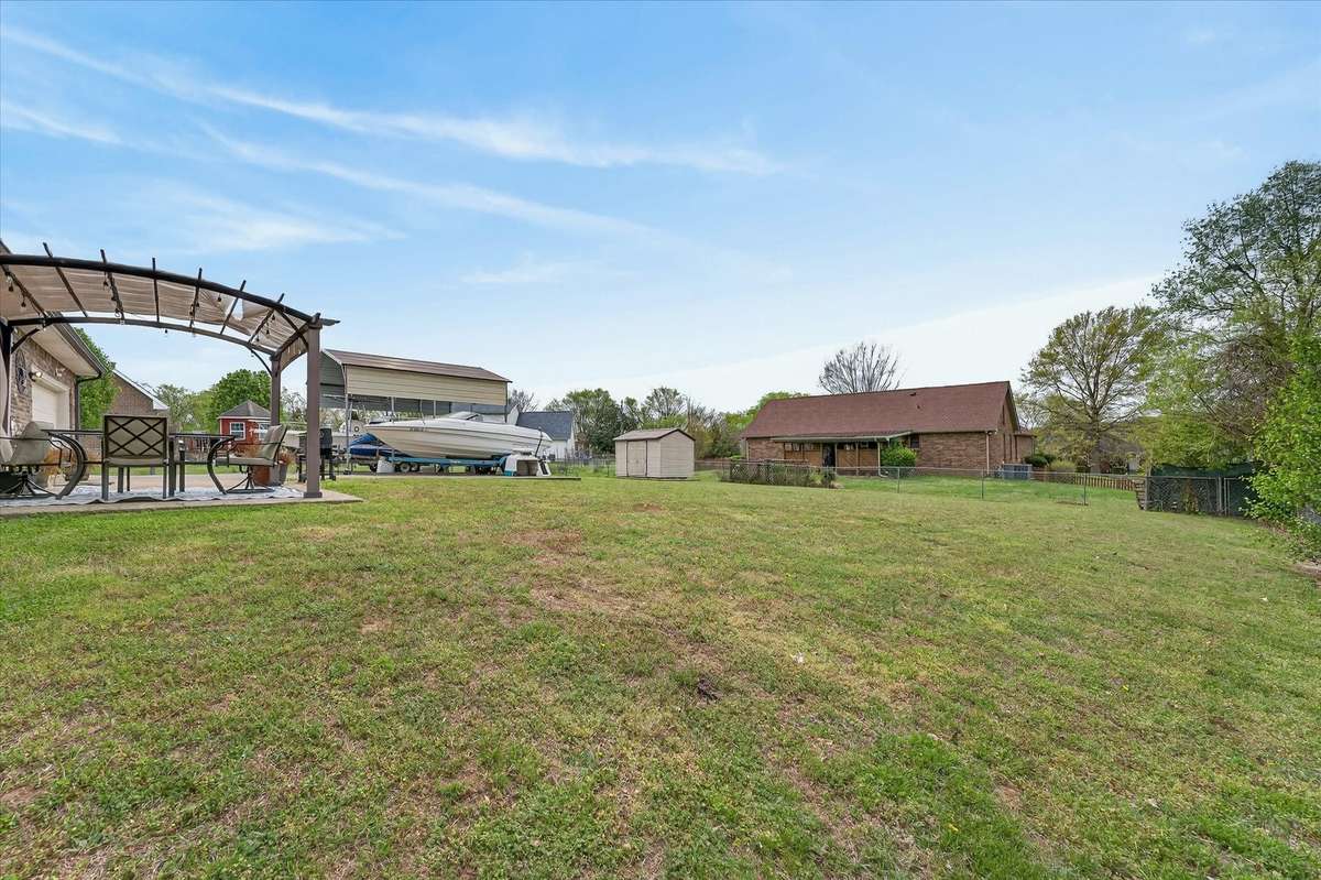Large level fenced in lot with carport, pergola, and storage building
