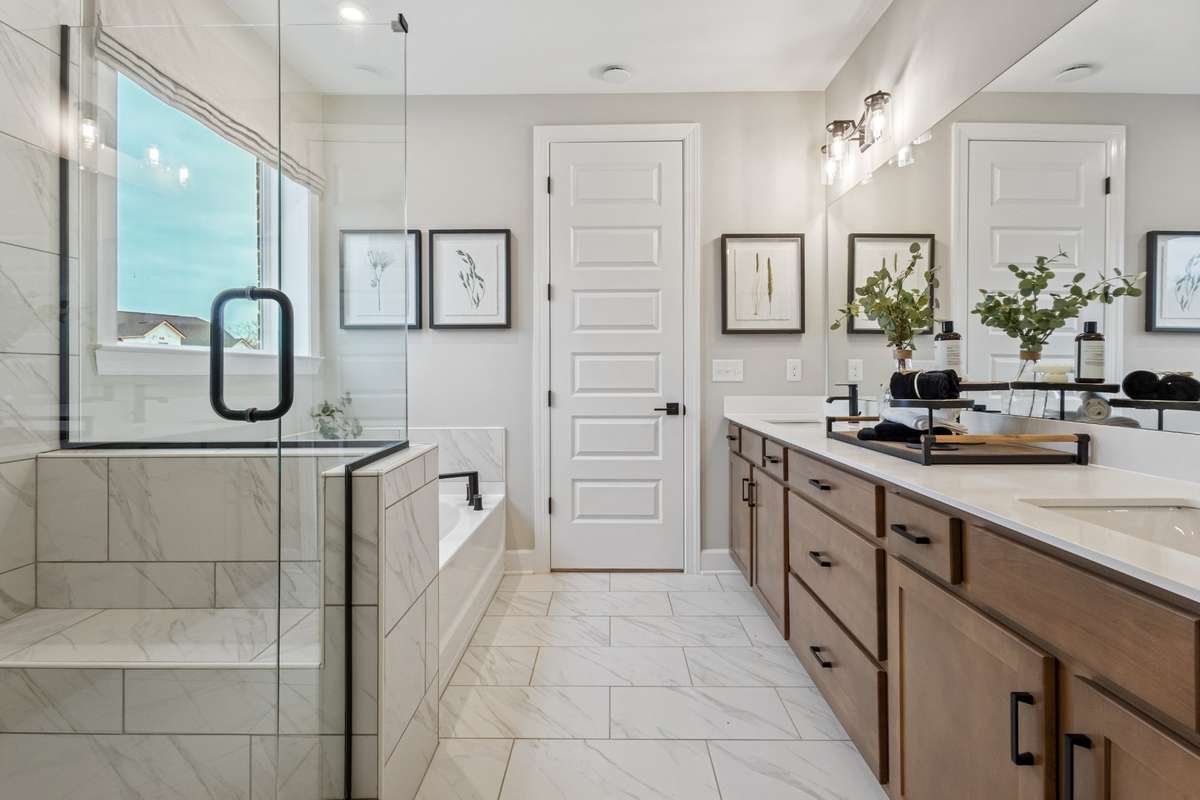 Live in luxury in your primary suite bathroom featuring double vanities, quartz counters, ceramic tile floors and shower wall, and tons of storage space!