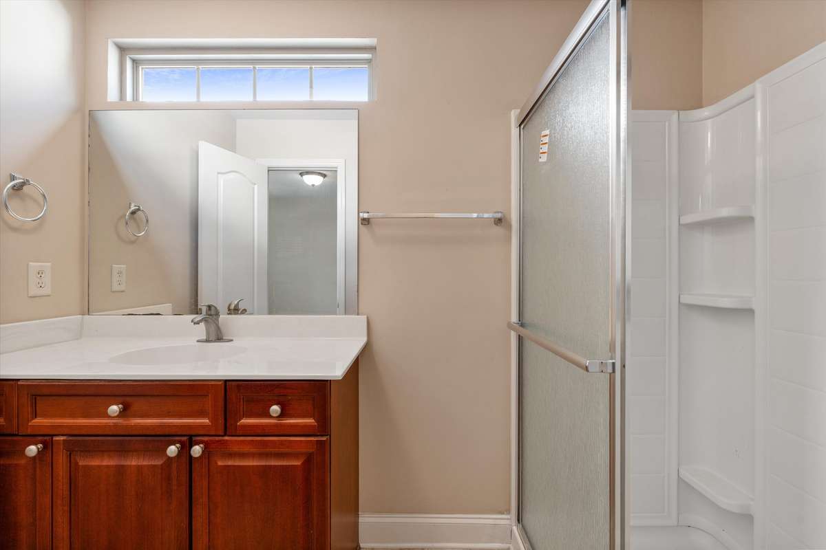 Clean and functional en-suite bath featuring a walk-in shower and ample vanity space 