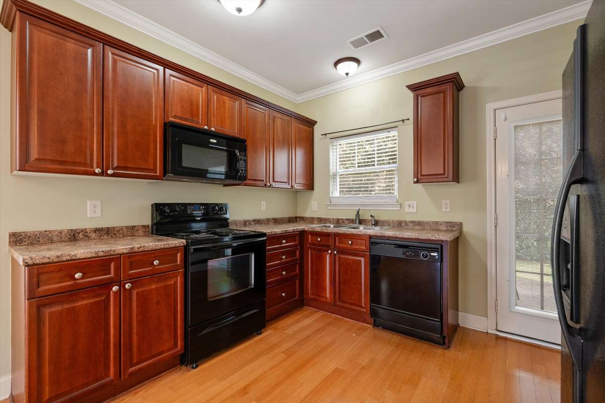 Functional kitchen with ample cabinet space, black appliances, and easy access to the patio 
